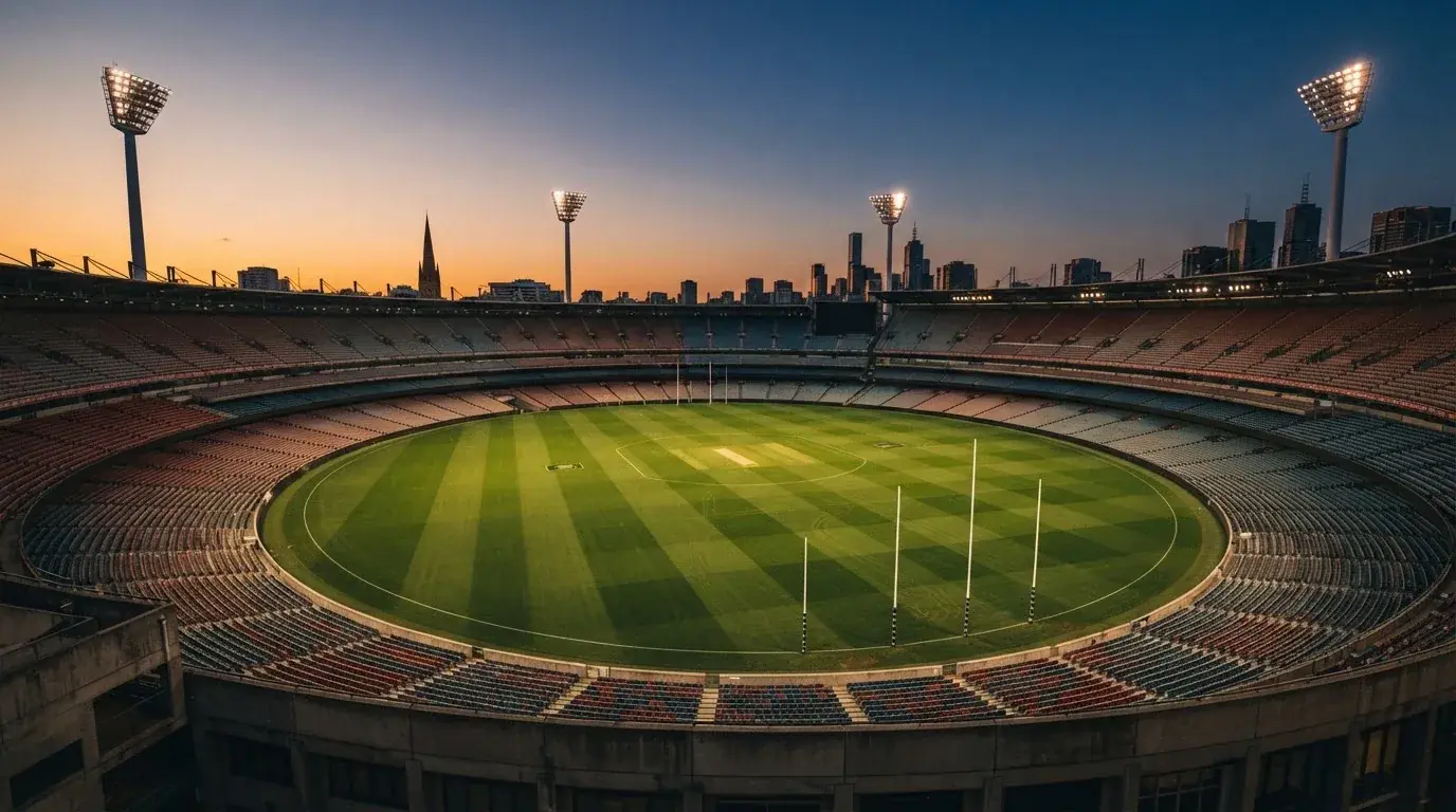 An empty football stadium with floodlight masts at dusk