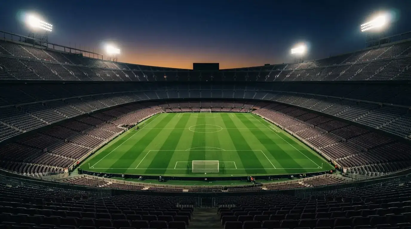 An empty football stadium with floodlight masts at dusk
