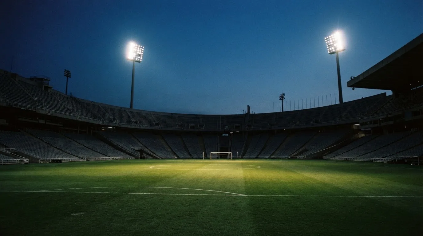 An empty football stadium with floodlight masts at dusk