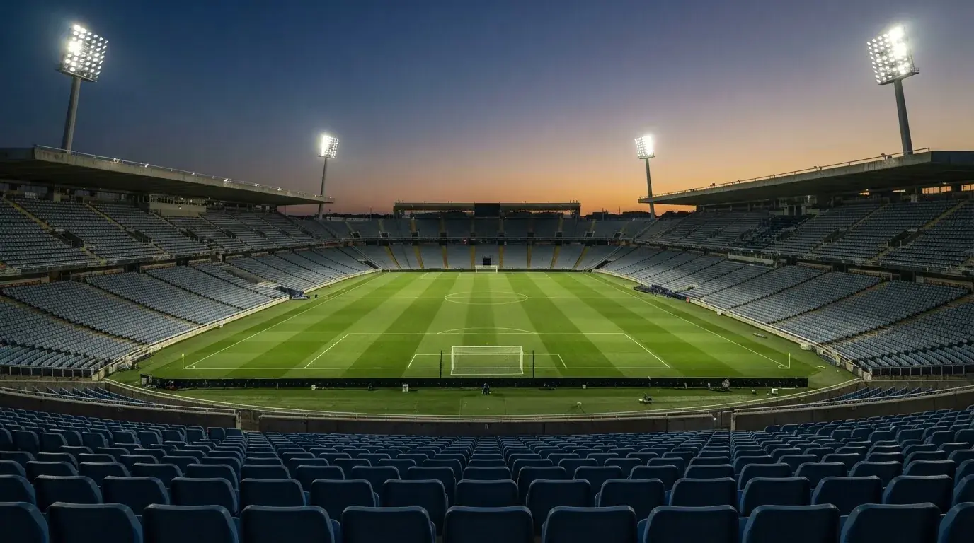 An empty football stadium with floodlight masts at dusk