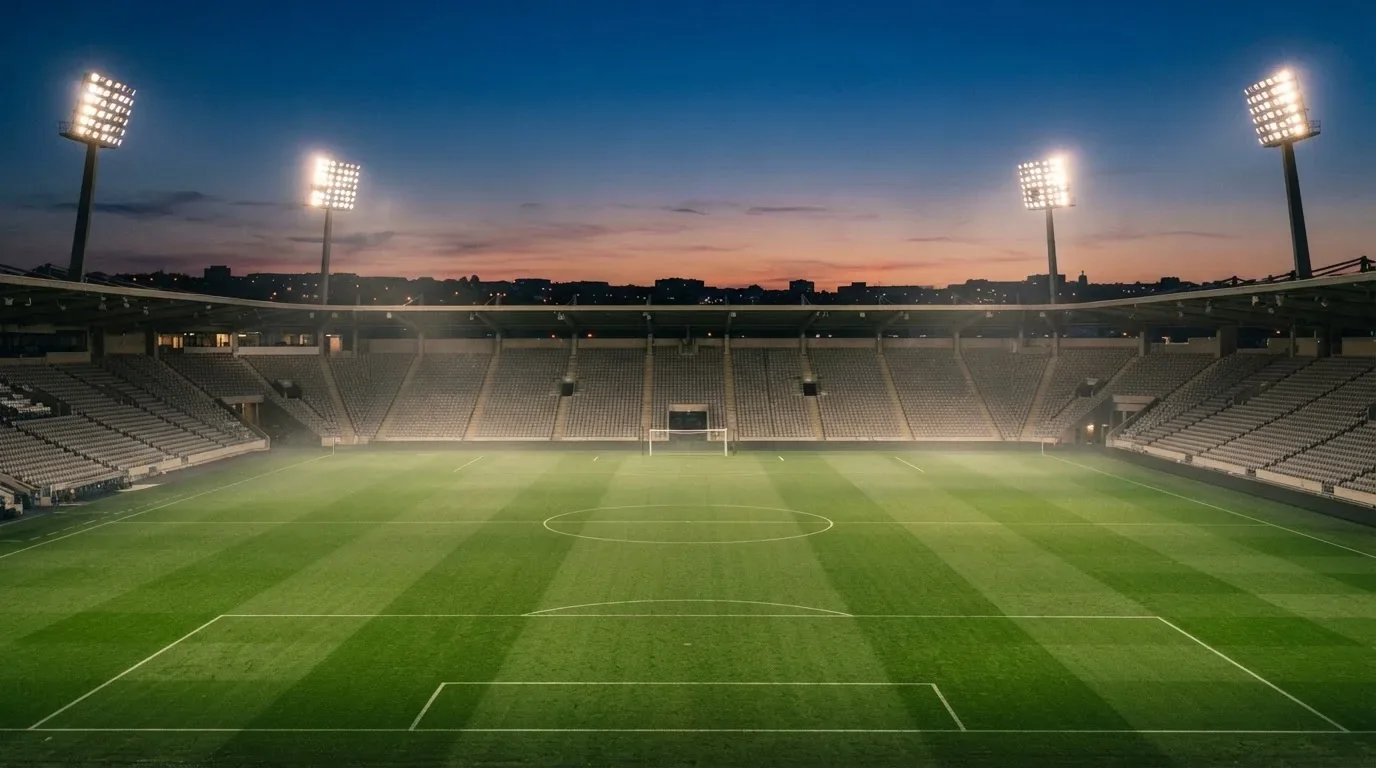 An empty football stadium with floodlight masts at dusk