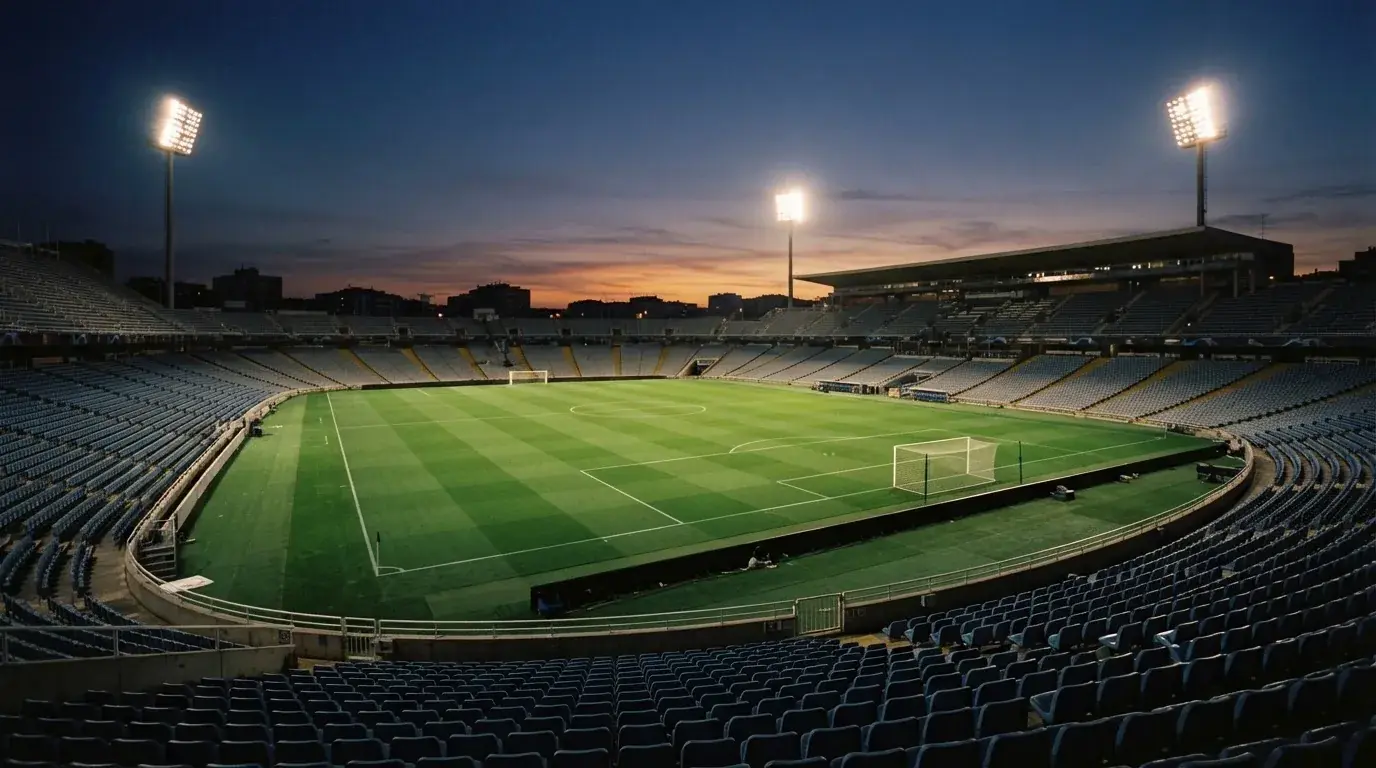 An empty football stadium with floodlight masts at dusk