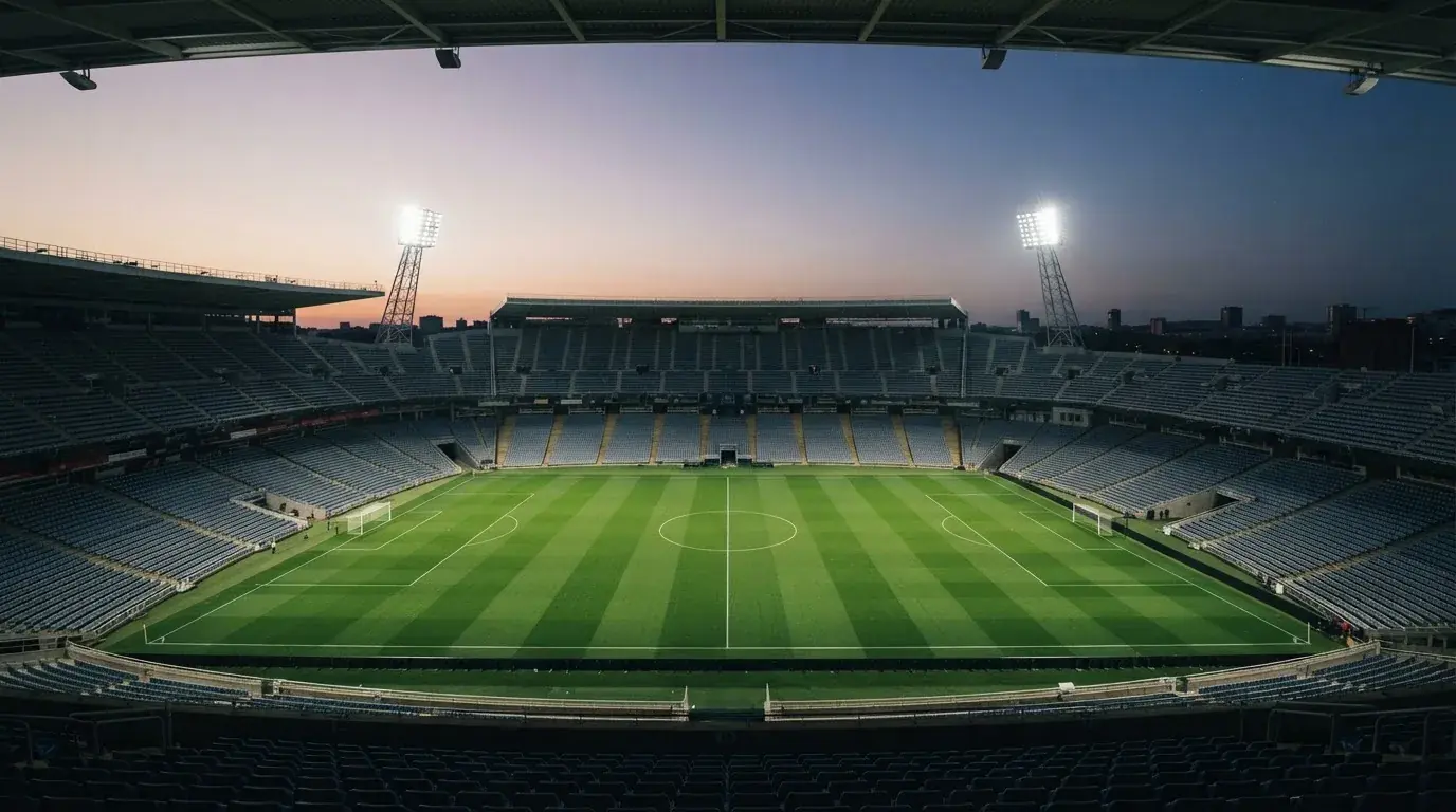 An empty football stadium with floodlight masts at dusk