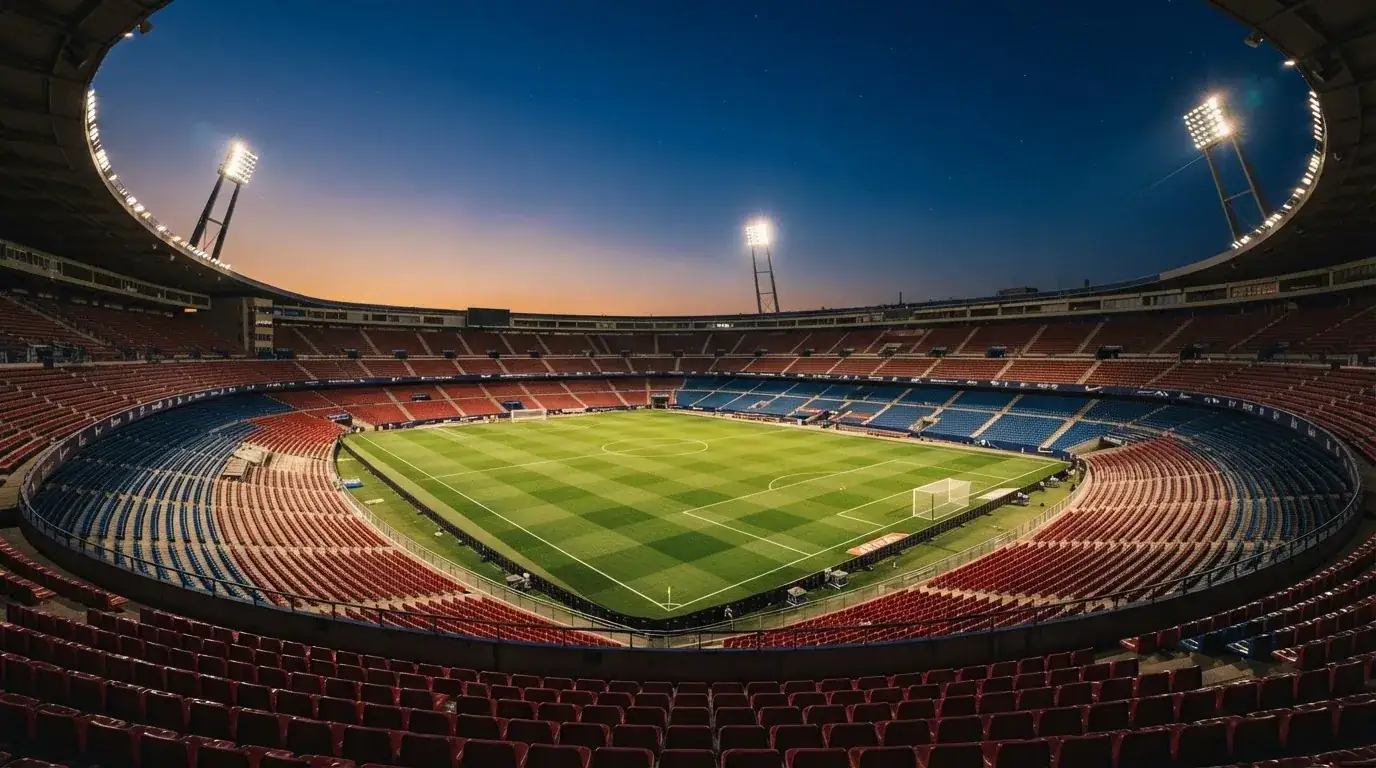 An empty football stadium with floodlight masts at dusk