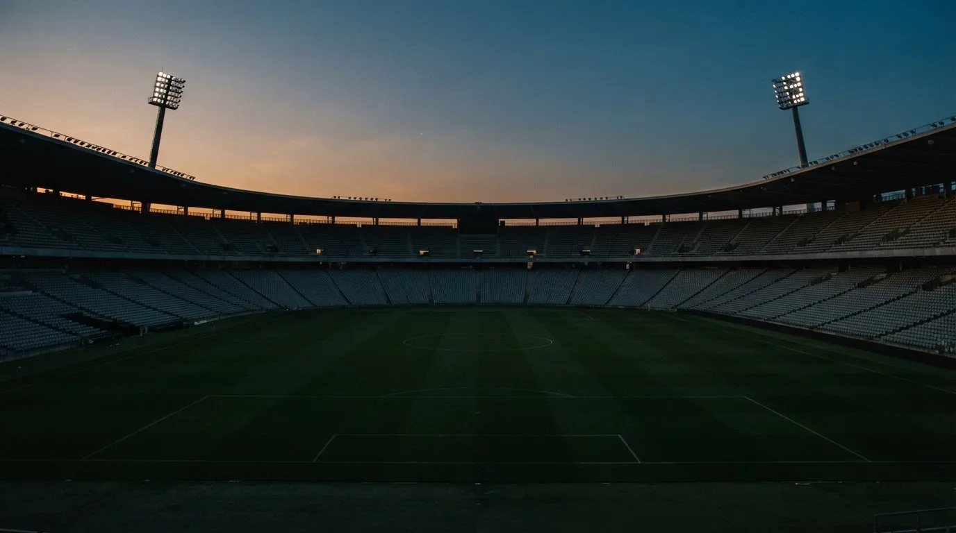 An empty football stadium with floodlight masts at dusk