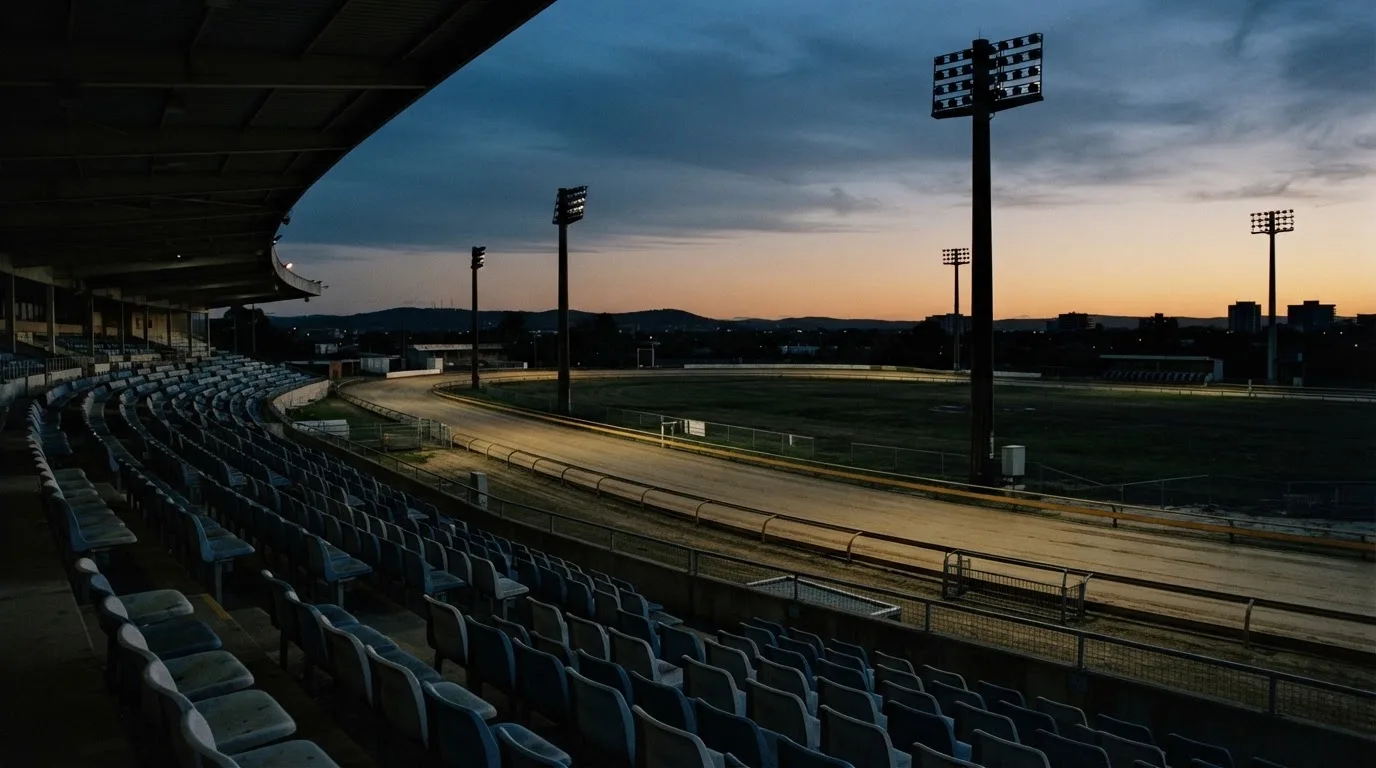 An empty football stadium with floodlight masts at dusk