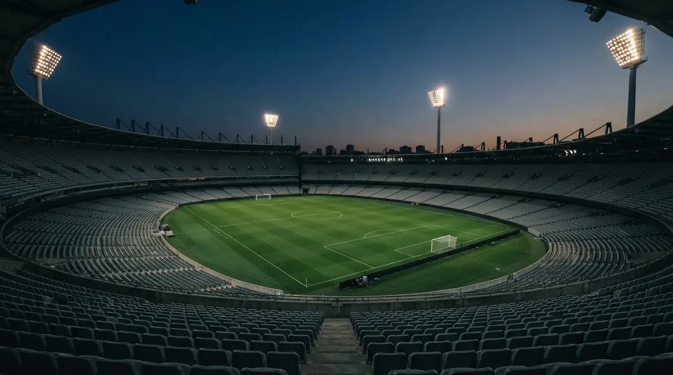 An empty football stadium with floodlight masts at dusk