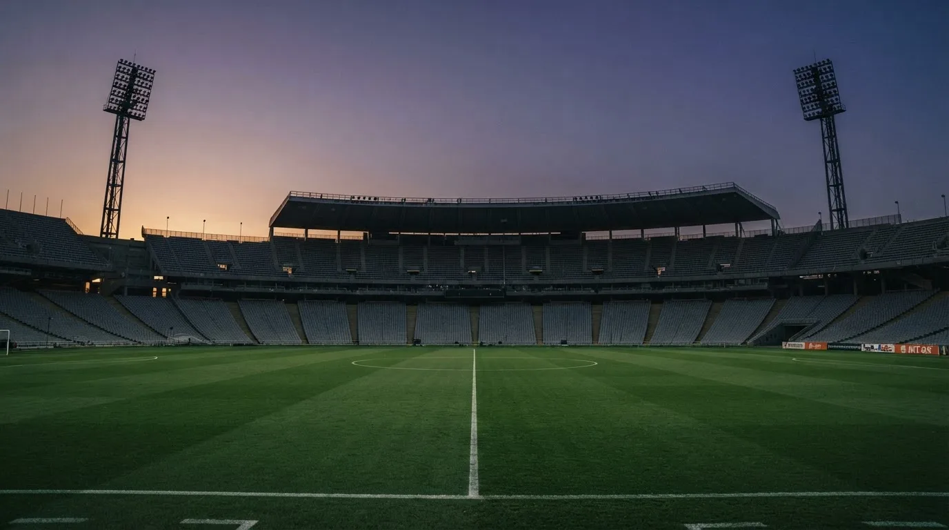 An empty football stadium with floodlight masts at dusk