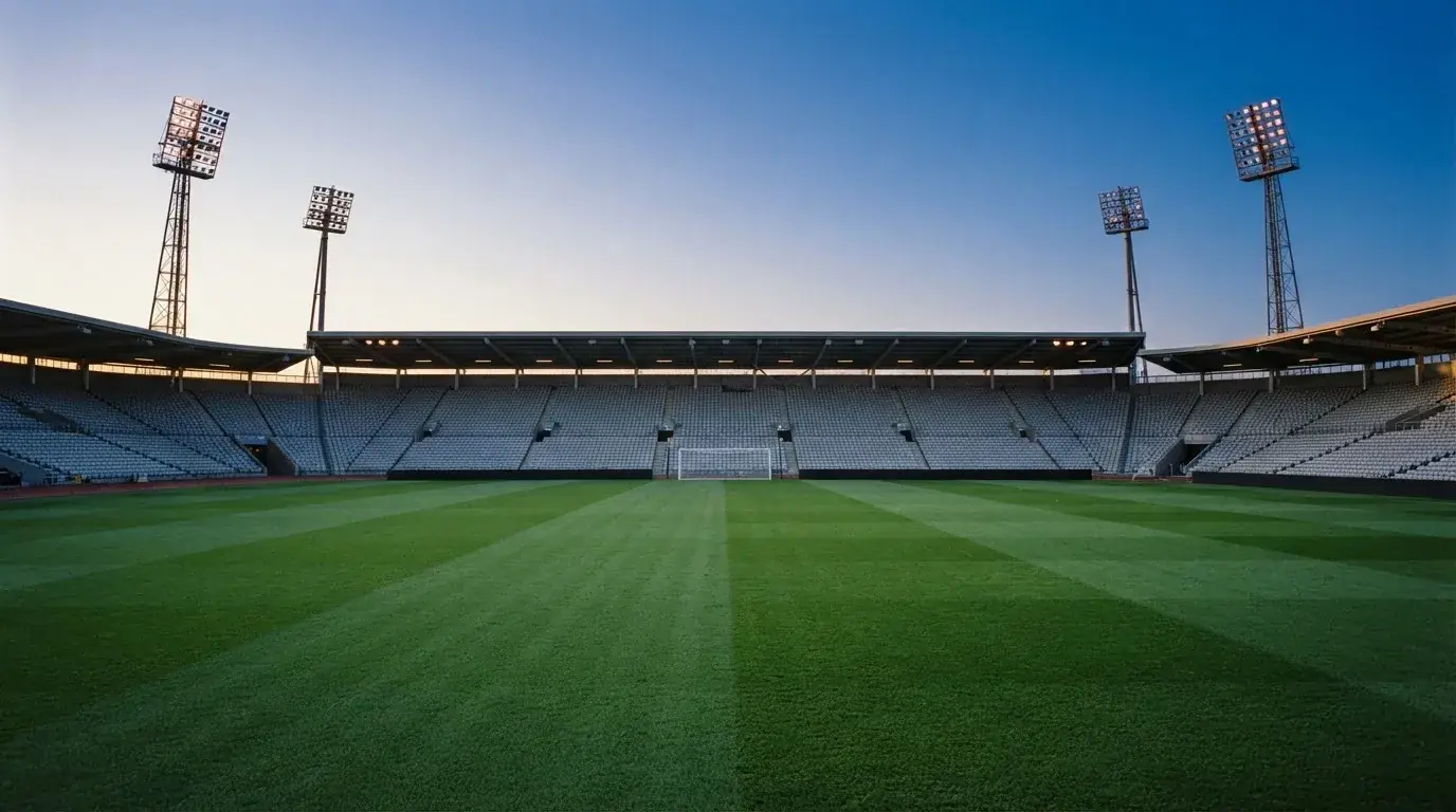 An empty football stadium with floodlight masts at dusk