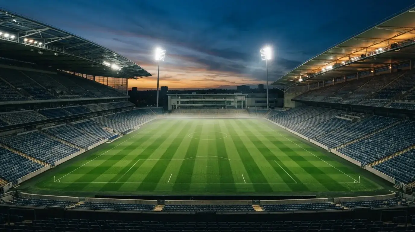 An empty football stadium with floodlight masts at dusk