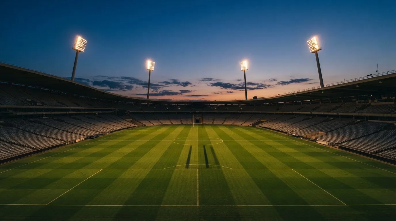 An empty football stadium with floodlight masts at dusk