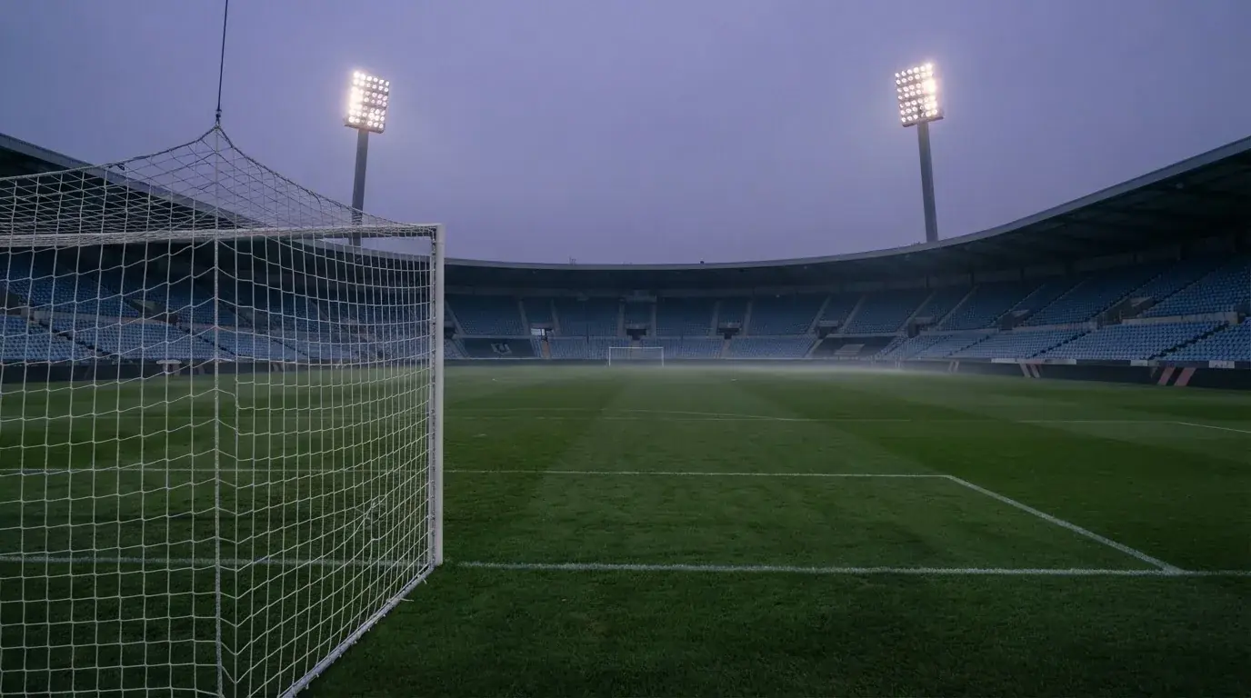 An empty football stadium with floodlight masts at dusk