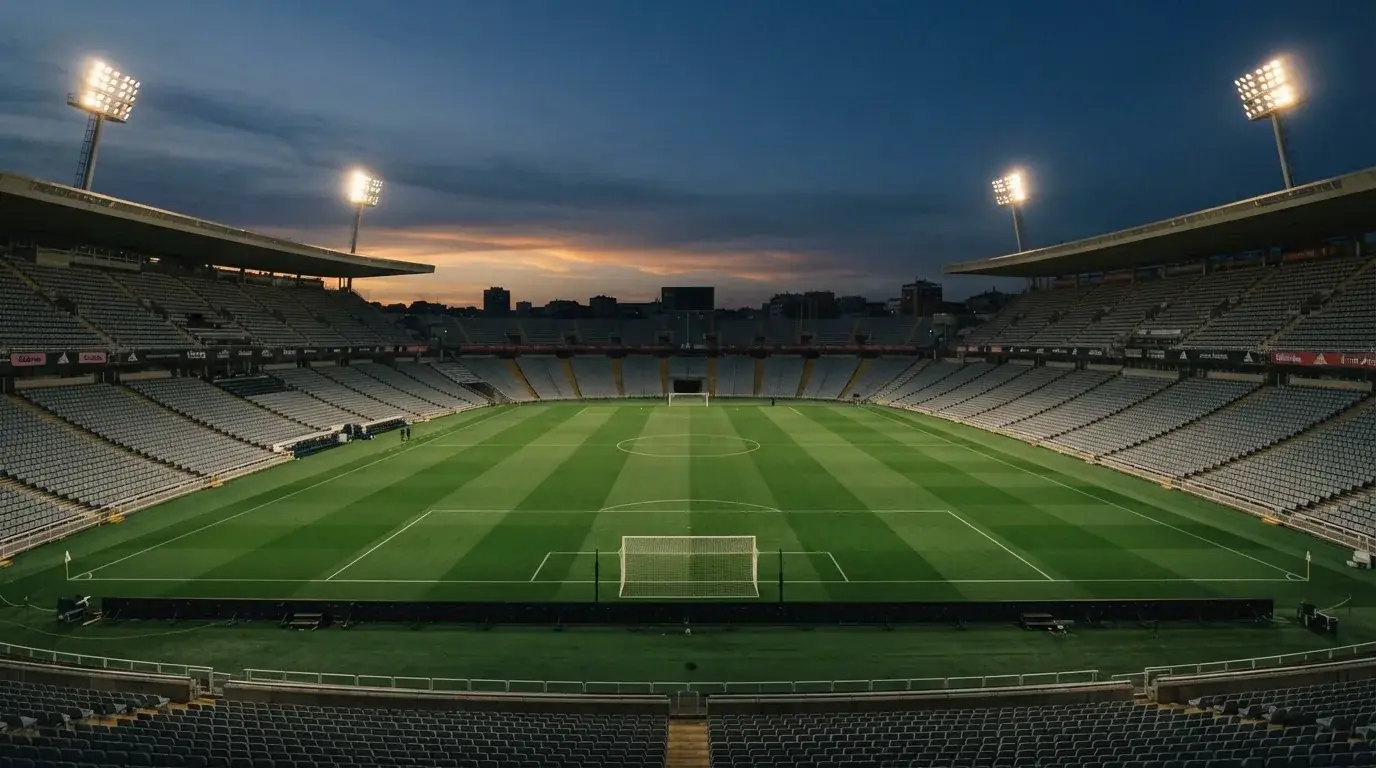 An empty football stadium with floodlight masts at dusk